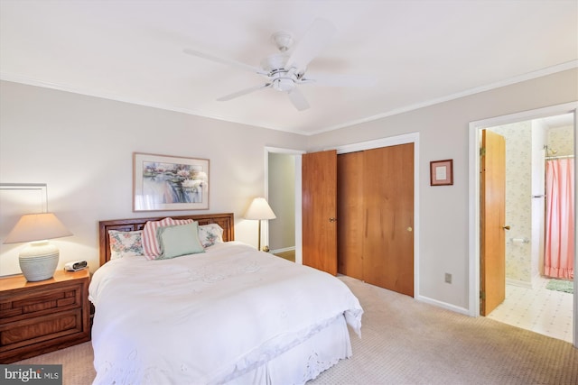 carpeted bedroom with a closet, ornamental molding, a ceiling fan, ensuite bath, and baseboards