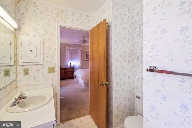 half bathroom with wallpapered walls, connected bathroom, crown molding, and vanity