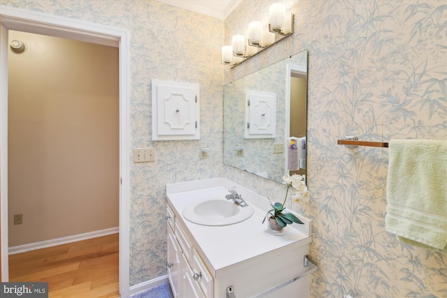 bathroom featuring wallpapered walls, baseboards, wood finished floors, and vanity