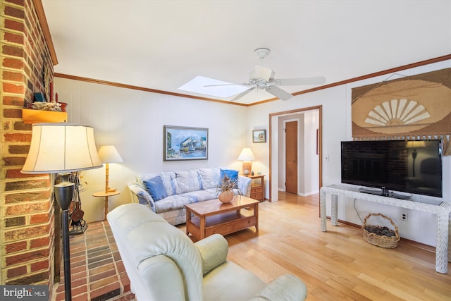 living area with ornamental molding, a skylight, ceiling fan, and wood finished floors