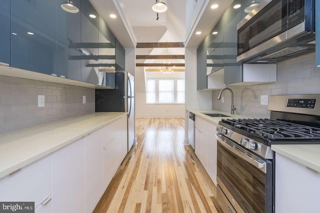 kitchen with open shelves, appliances with stainless steel finishes, light wood-style floors, a sink, and modern cabinets