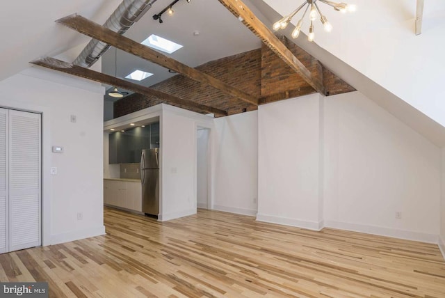 interior space featuring a skylight, baseboards, wood finished floors, an inviting chandelier, and high vaulted ceiling