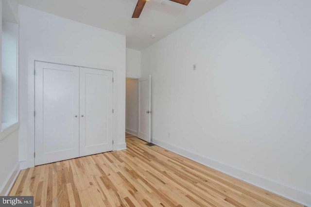 unfurnished bedroom with a closet, wood finished floors, a ceiling fan, and baseboards