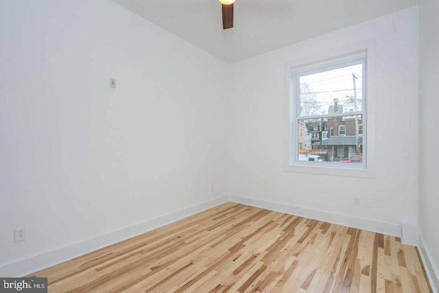 spare room with wood finished floors, a ceiling fan, and baseboards