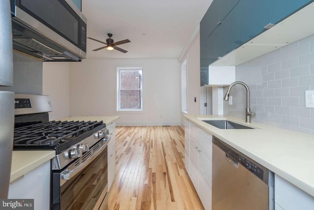 kitchen featuring stainless steel appliances, a sink, light wood-style floors, light countertops, and decorative backsplash