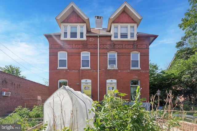 view of front facade with brick siding and a chimney