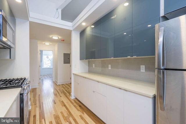 kitchen with stainless steel appliances, modern cabinets, backsplash, and light wood-style floors