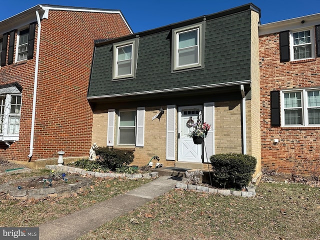 view of front of property featuring a shingled roof, mansard roof, and brick siding