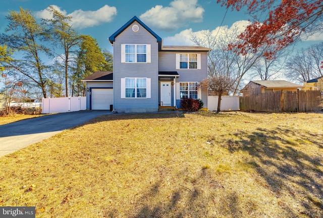 traditional-style home with aphalt driveway, a front yard, fence, and an attached garage