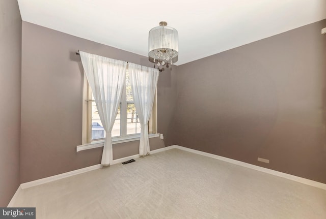 unfurnished room featuring a notable chandelier, light carpet, and baseboards