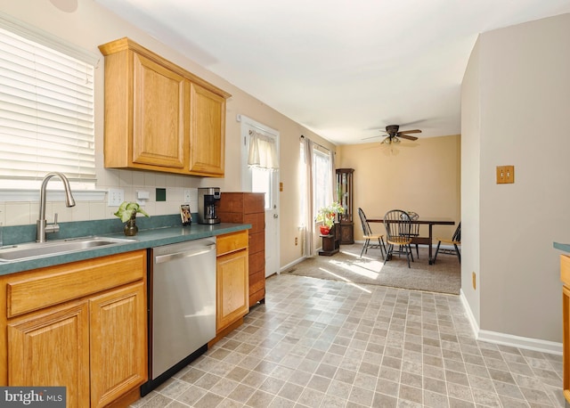 kitchen featuring baseboards, a ceiling fan, dishwasher, backsplash, and a sink