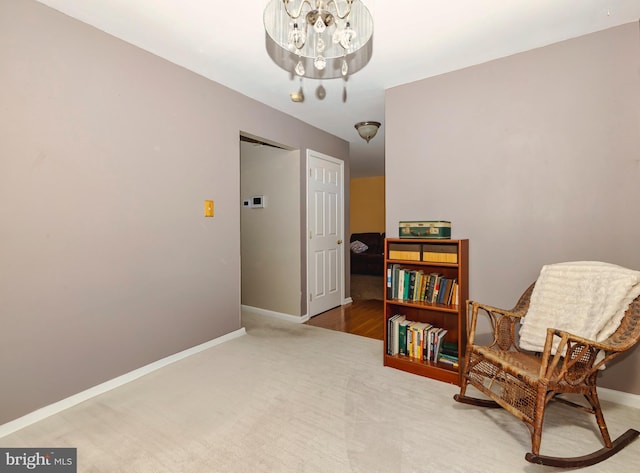 living area featuring baseboards, a notable chandelier, and carpet flooring