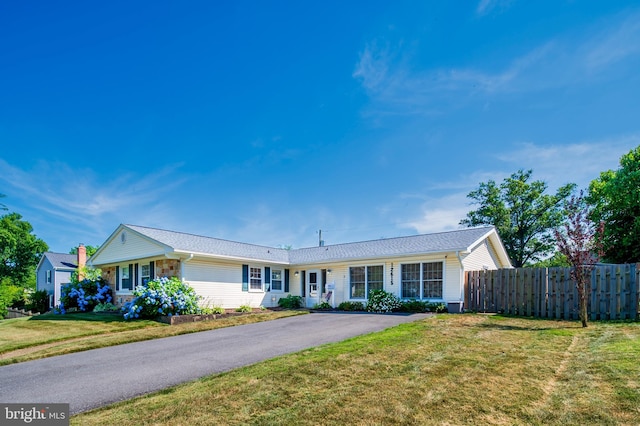 ranch-style home with aphalt driveway, a front yard, and fence