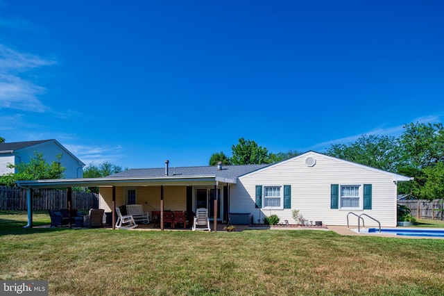 rear view of property featuring a fenced in pool, fence, a lawn, and a patio