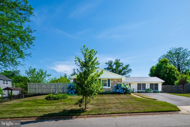 view of front of house featuring stone siding, aphalt driveway, a front yard, and fence