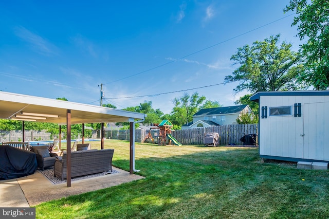 view of yard featuring an outbuilding, a patio, a playground, a fenced backyard, and a storage unit