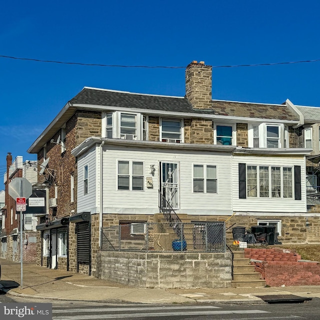 view of front facade with stone siding and a chimney