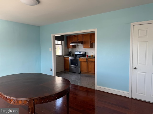 kitchen with brown cabinets, stainless steel electric stove, tasteful backsplash, wood finished floors, and under cabinet range hood