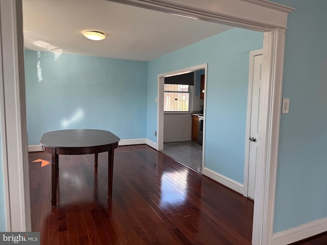 unfurnished dining area featuring wood-type flooring and baseboards