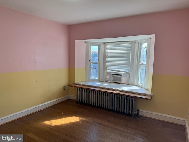 unfurnished room with radiator, plenty of natural light, and wood-type flooring