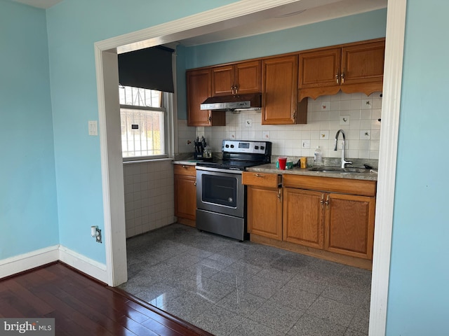 kitchen featuring electric range, baseboards, brown cabinets, under cabinet range hood, and a sink