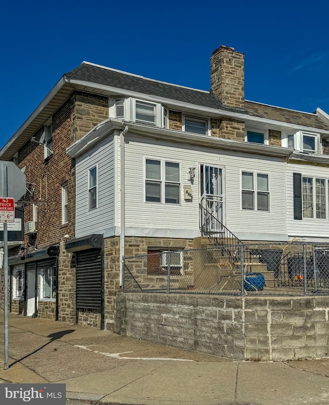 exterior space featuring entry steps, stone siding, and a chimney