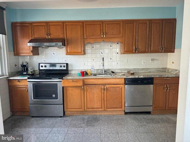 kitchen featuring under cabinet range hood, a sink, light countertops, appliances with stainless steel finishes, and brown cabinets