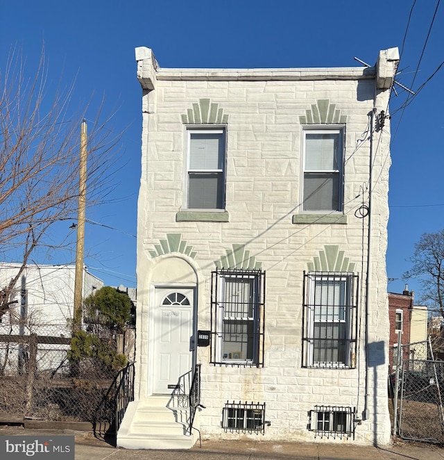 townhome / multi-family property featuring stone siding and fence