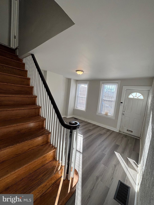 foyer with stairs, dark wood finished floors, visible vents, and baseboards