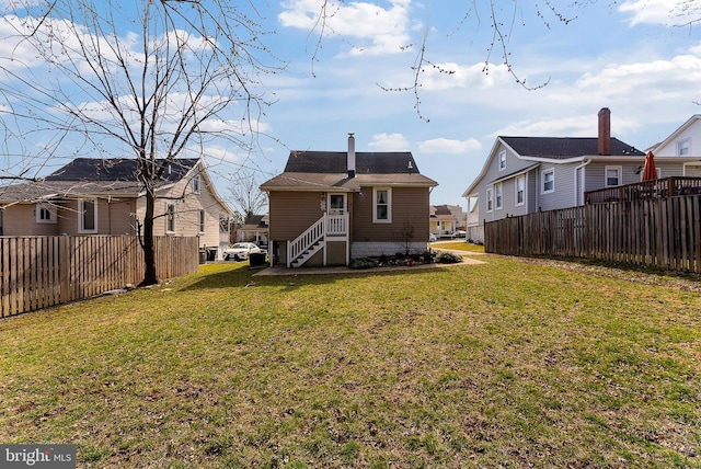 rear view of house featuring a yard, a residential view, fence, and a chimney