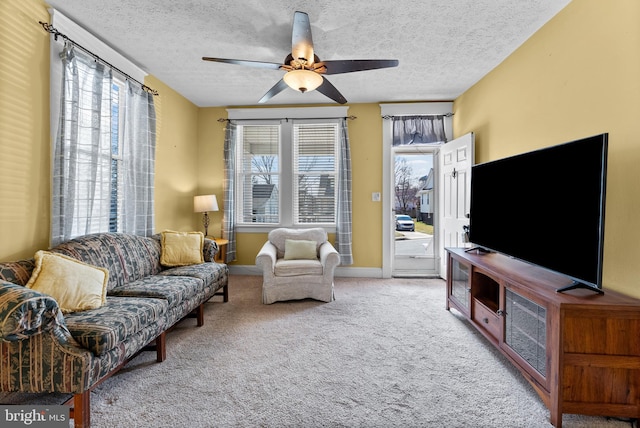 carpeted living room with ceiling fan, a textured ceiling, and baseboards