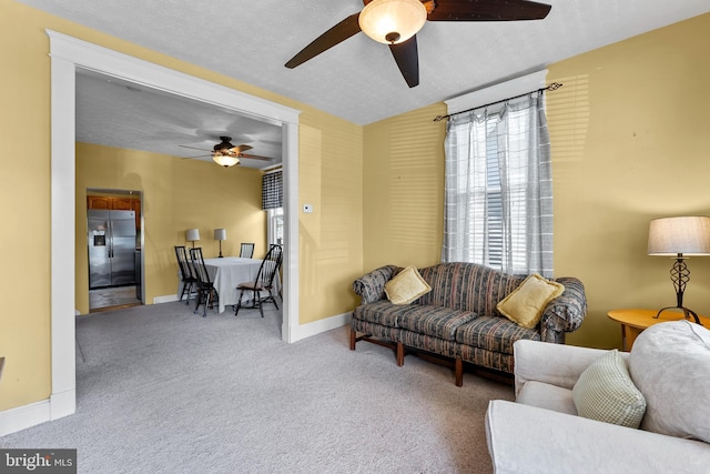 carpeted living room featuring a ceiling fan, a textured ceiling, and baseboards