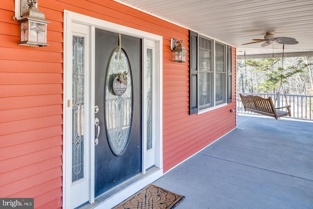 view of exterior entry featuring ceiling fan and a porch