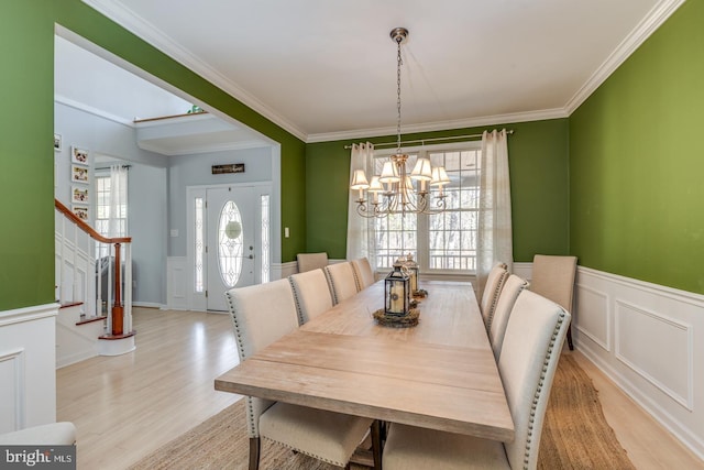 dining room featuring an inviting chandelier, stairs, ornamental molding, and light wood-style floors