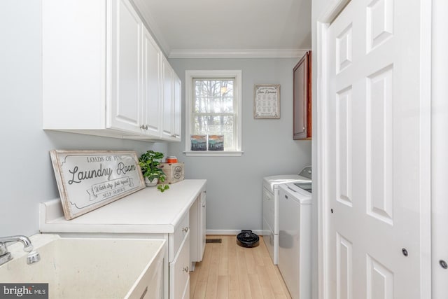 laundry room featuring light wood-style flooring, a sink, washer and dryer, ornamental molding, and cabinet space