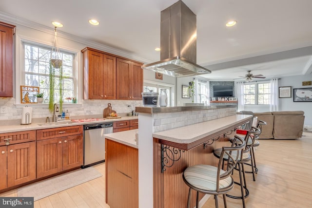 kitchen featuring island range hood, a sink, a kitchen breakfast bar, open floor plan, and dishwasher