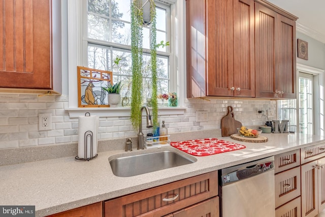 kitchen with plenty of natural light, brown cabinets, a sink, and stainless steel dishwasher