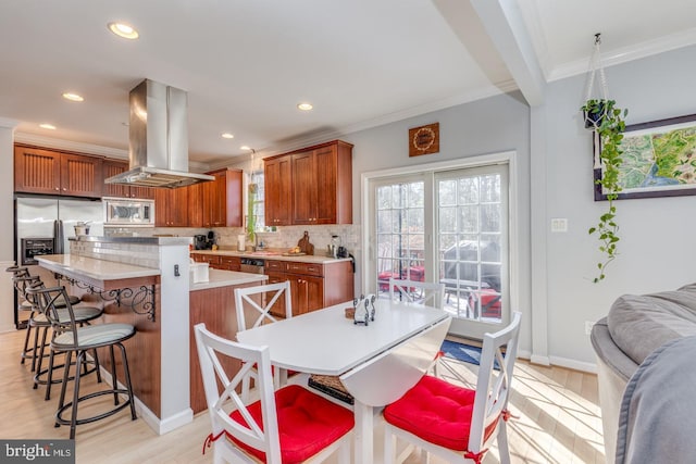 kitchen featuring ornamental molding, island exhaust hood, appliances with stainless steel finishes, and decorative backsplash