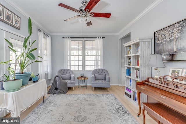 living area with baseboards, a ceiling fan, crown molding, and wood finished floors