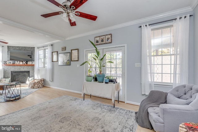 living area featuring a ceiling fan, ornamental molding, a wealth of natural light, and wood finished floors