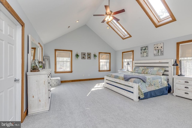 carpeted bedroom featuring a skylight, baseboards, high vaulted ceiling, and ceiling fan