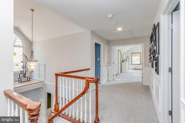 hall featuring attic access, carpet, vaulted ceiling, and an upstairs landing