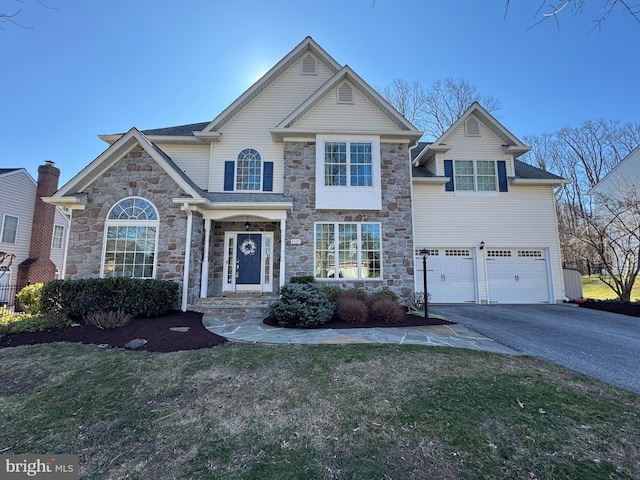 traditional-style house featuring aphalt driveway, a front lawn, and a garage