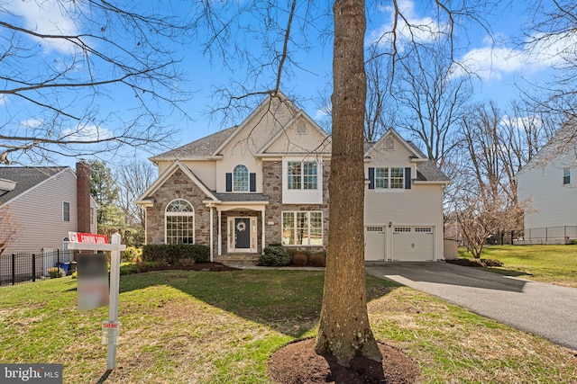 view of front of property with a front lawn, fence, a garage, stone siding, and driveway