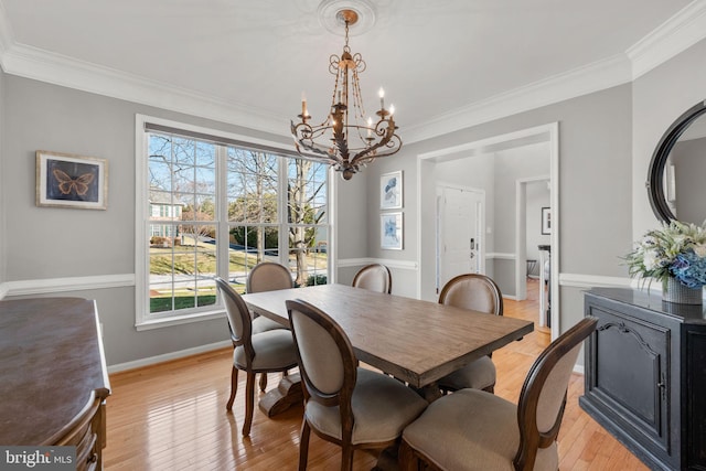 dining space with baseboards, a notable chandelier, ornamental molding, and light wood finished floors