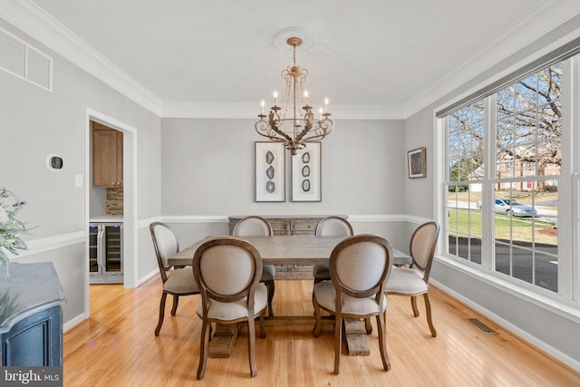 dining space with wine cooler, visible vents, light wood-type flooring, and ornamental molding