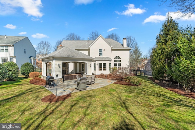 rear view of property featuring fence, a chimney, a patio area, a lawn, and an outdoor hangout area