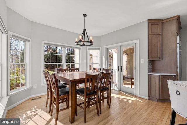 dining space featuring visible vents, baseboards, a chandelier, french doors, and light wood-style floors