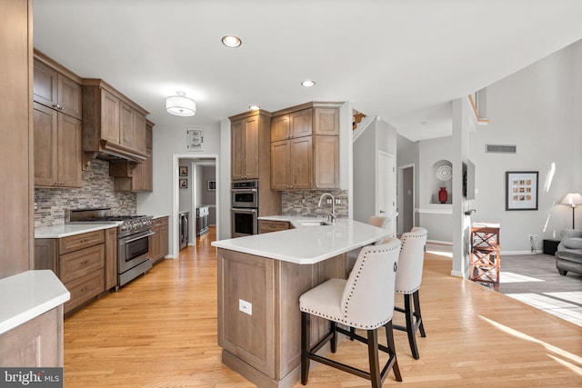 kitchen with visible vents, a sink, stainless steel appliances, a peninsula, and a breakfast bar area