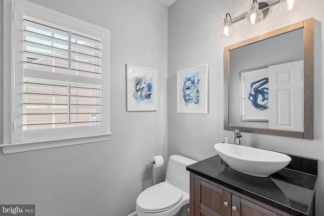 half bath with vanity, toilet, and a wealth of natural light